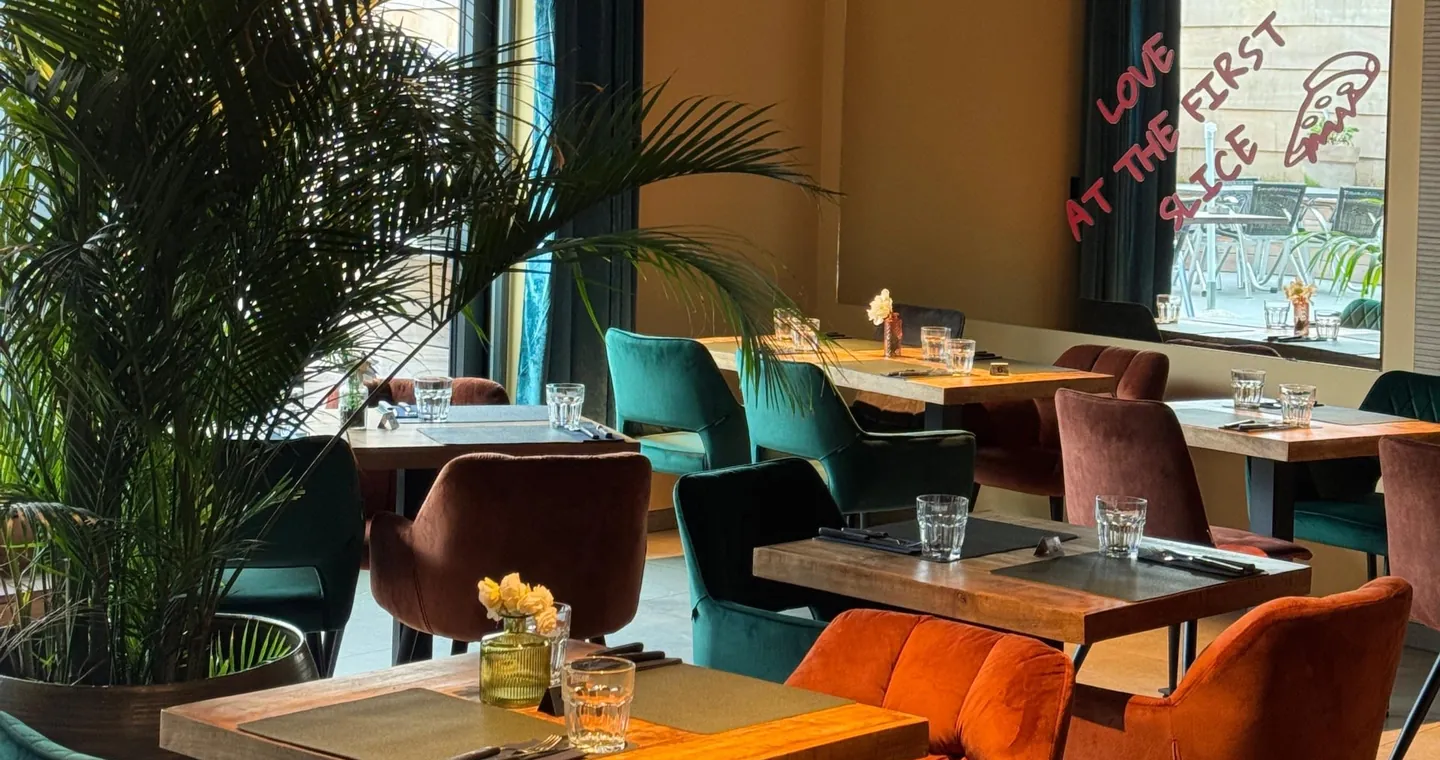La salle d'Amore : fauteuils en velours émeraude et rouille, palmiers et tables en bois